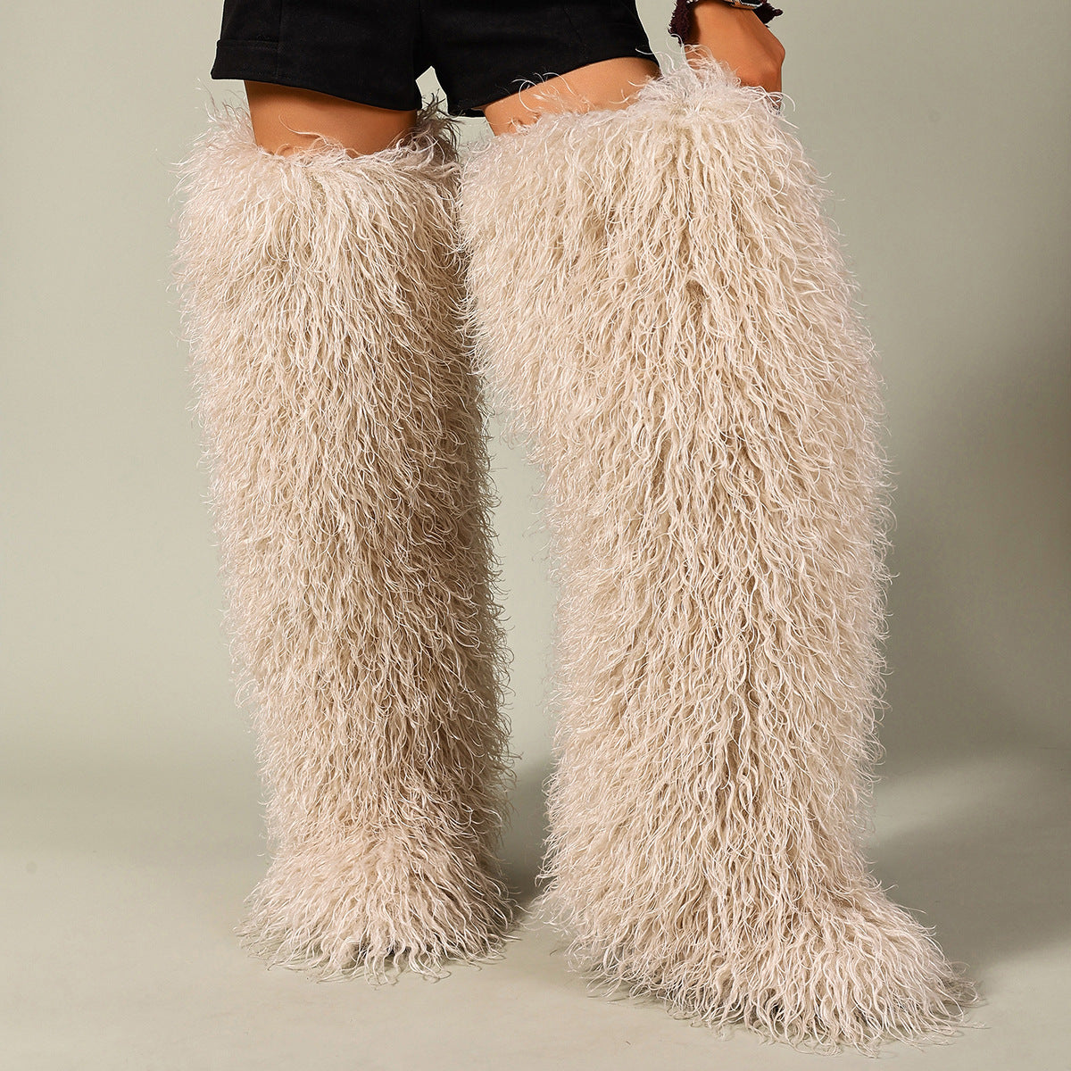 Cream faux-fur thigh-high boots with shaggy pile, shown worn on both legs.