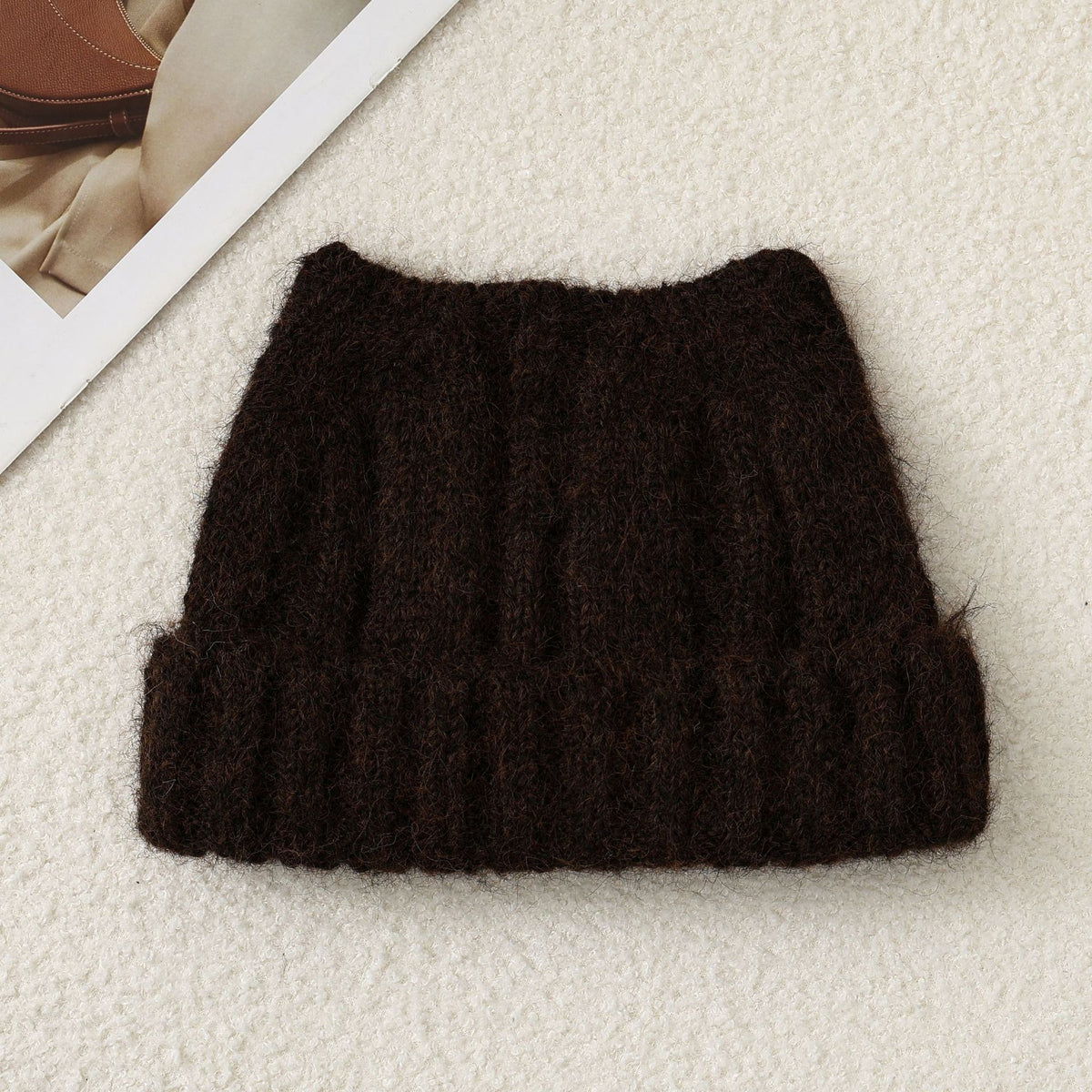 Dark brown cat-ear knit beanie, folded flat, thick fuzzy knit with ribbed band