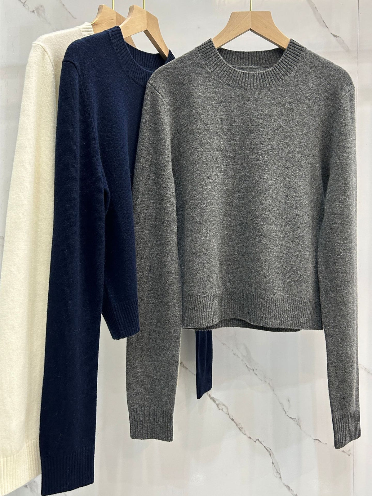 Slim crewneck knit sweater with ribbed cuffs and hem, gray and dark blue on hangers