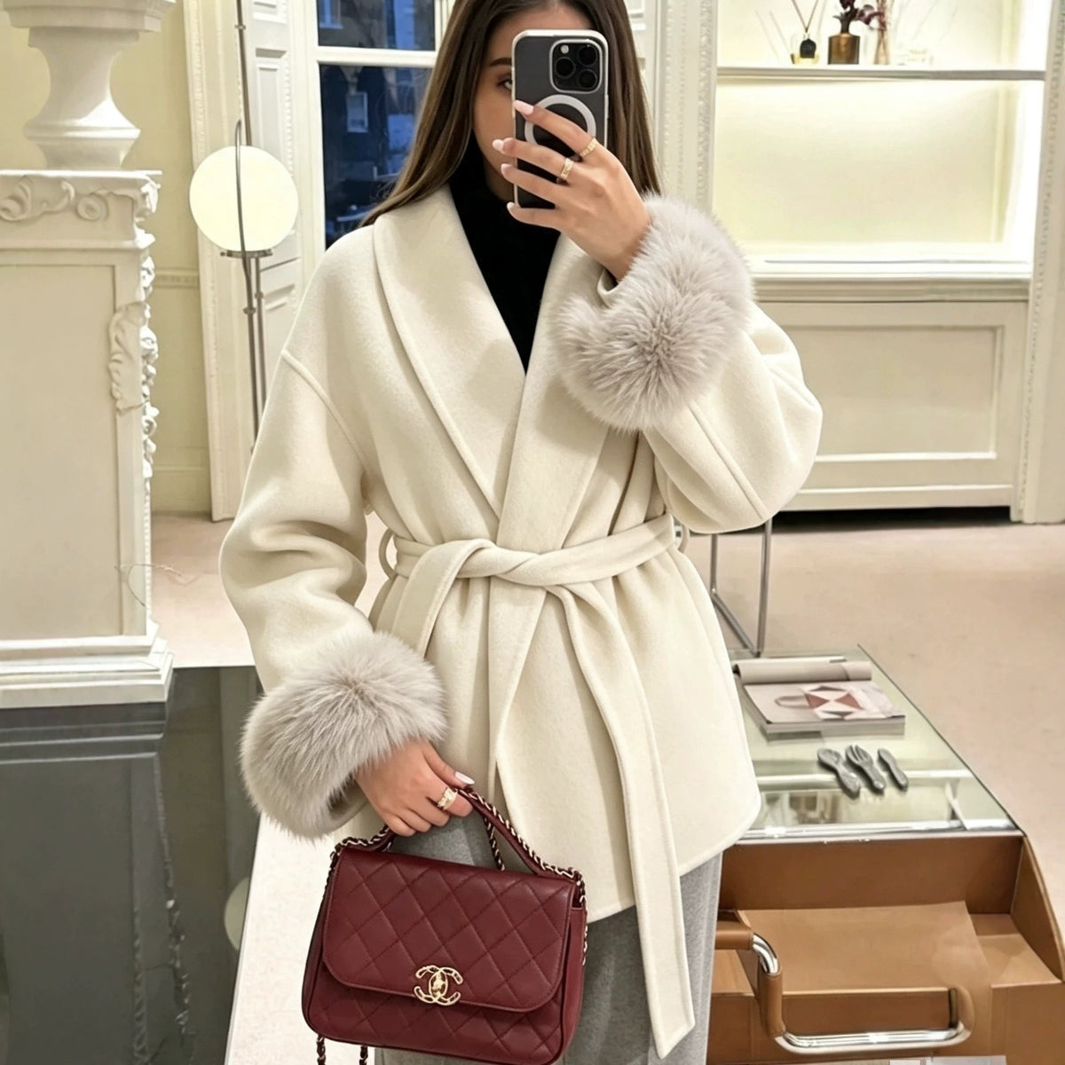 White wool wrap coat with V-neck, tie belt, and faux fur cuffed sleeves.