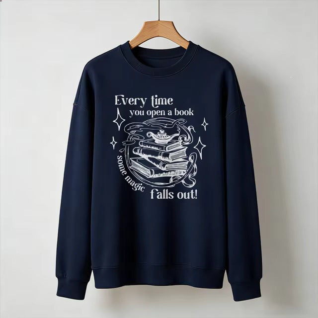 Navy blue crewneck sweatshirt with open-book magic graphic and starry text, long sleeves.