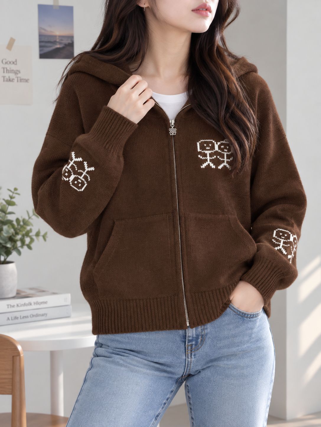 Brown zip-up hooded knit cardigan with graphic patches and front pockets.