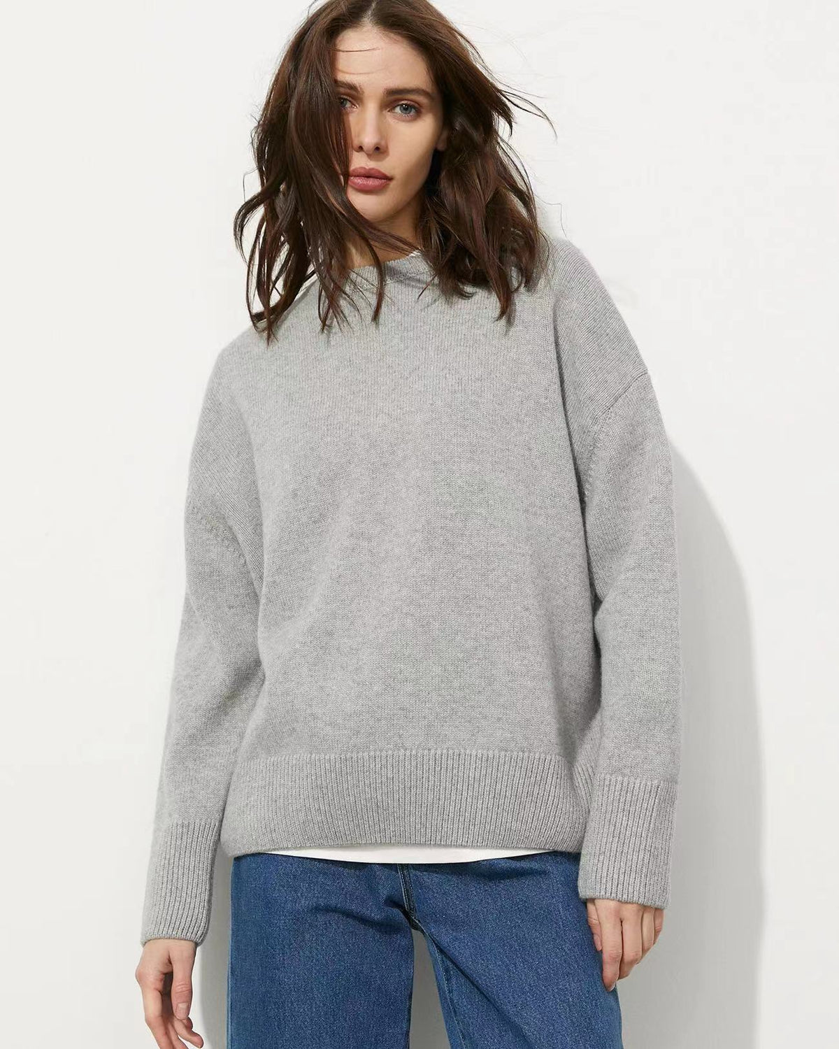 Light gray relaxed-fit sweater with ribbed cuffs and hem, shown with jeans