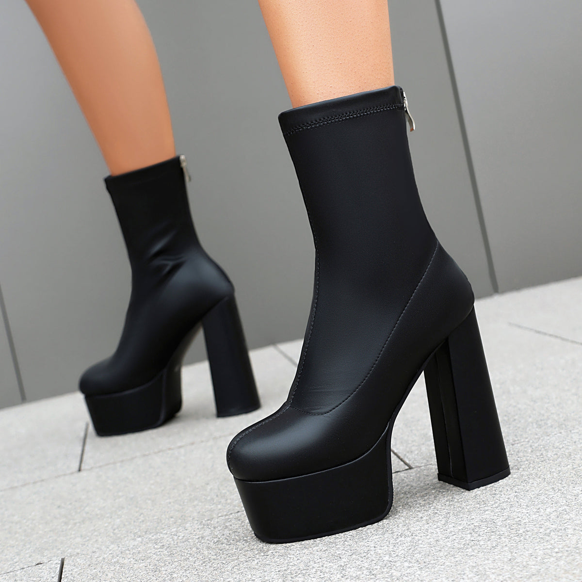 Black platform mid-calf boots on model with chunky block heel and thick sole