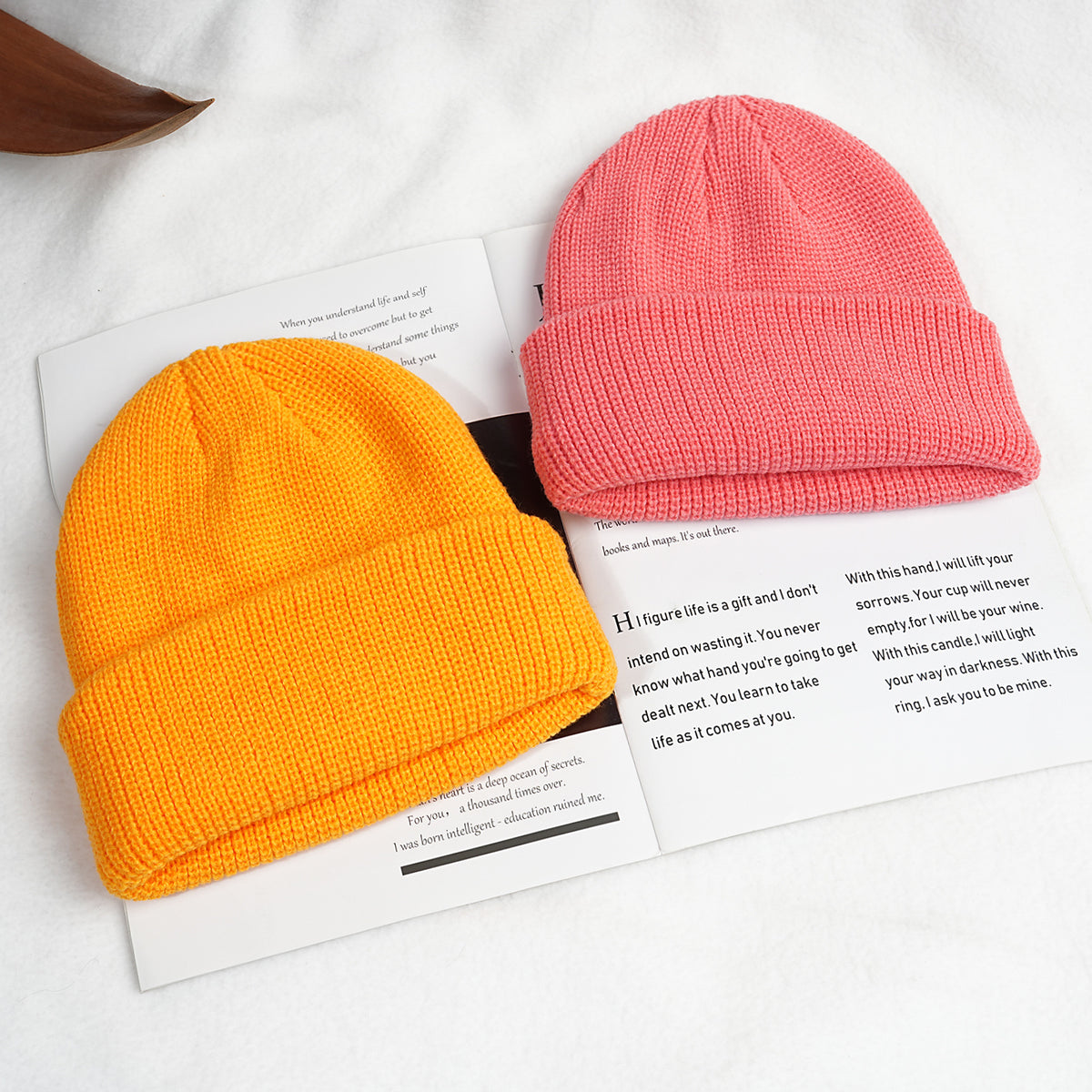 Thick knitted beanie hats in coral pink and orange, with ribbed cuff