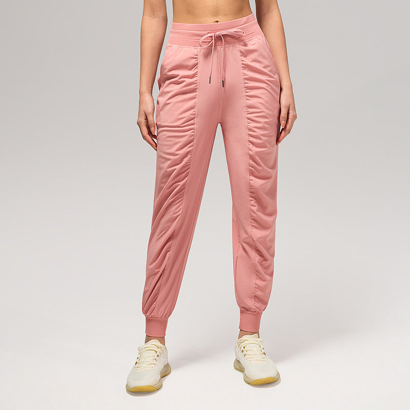 Women’s loose dusty pink jogger pants with drawstring waist and cuffed ankles, side pockets.