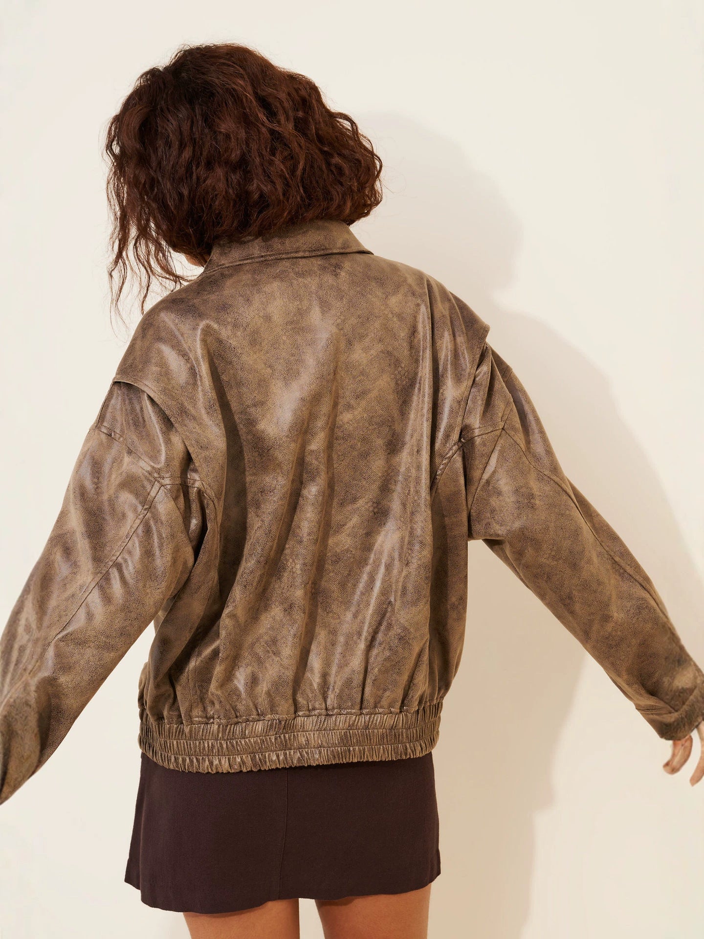 Back view of distressed brown faux leather bomber jacket with ribbed hem and cuffs