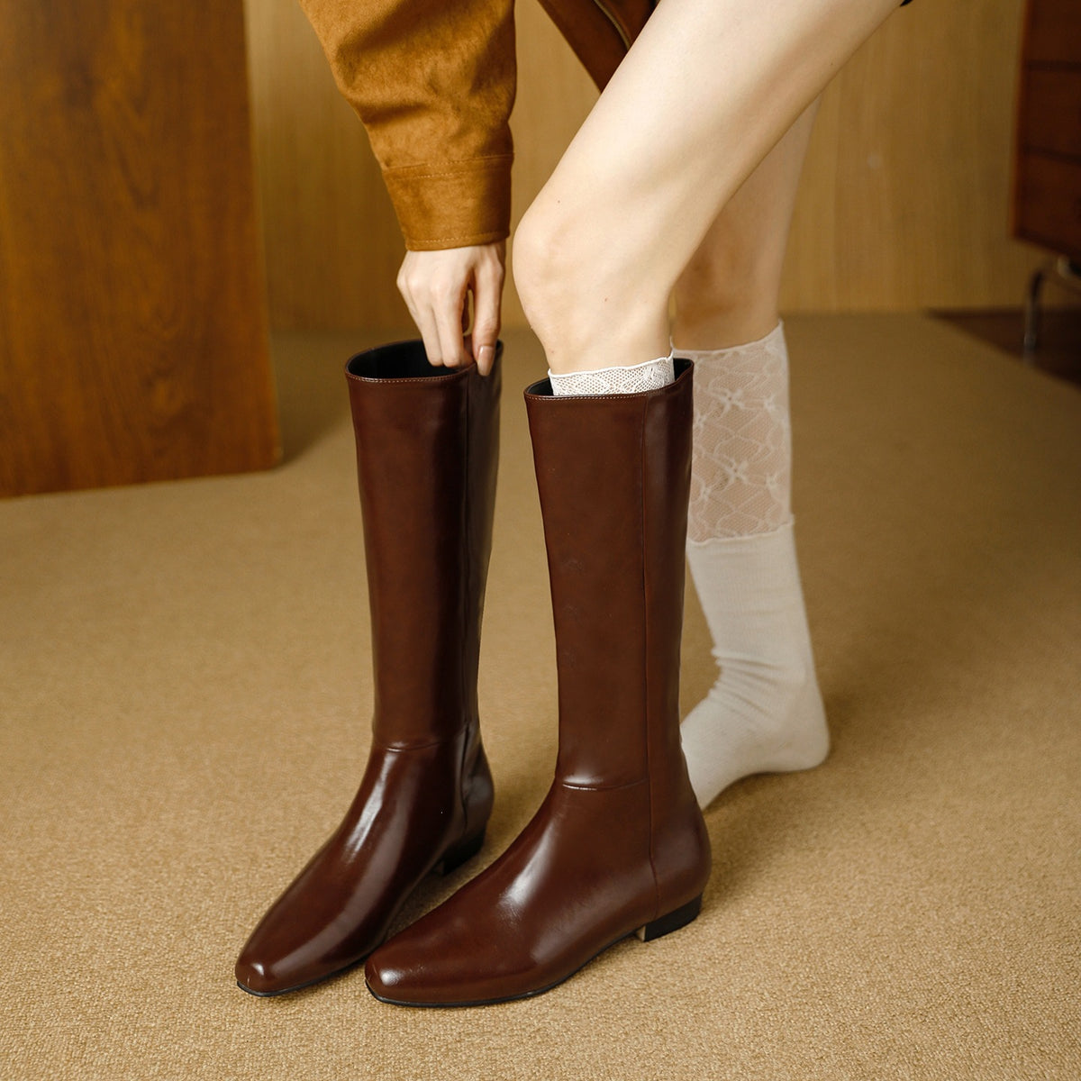 Brown knee-high leather boots with pointed toe and hidden low heel, with white socks