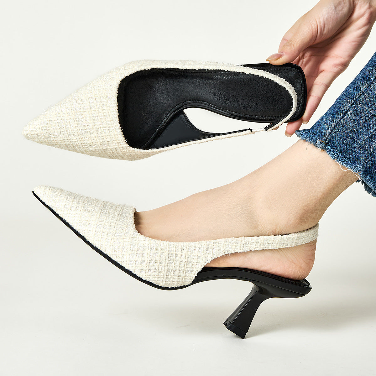 Cream pointed-toe high heel slingback pumps with black lining at opening