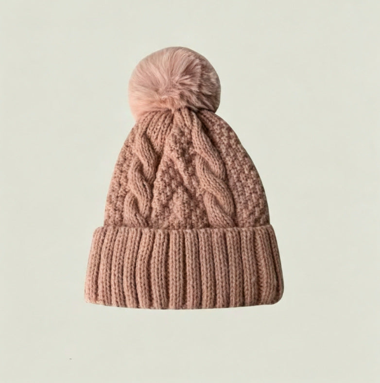 Pink cable-knit winter hat with ribbed cuff and fluffy pom-pom