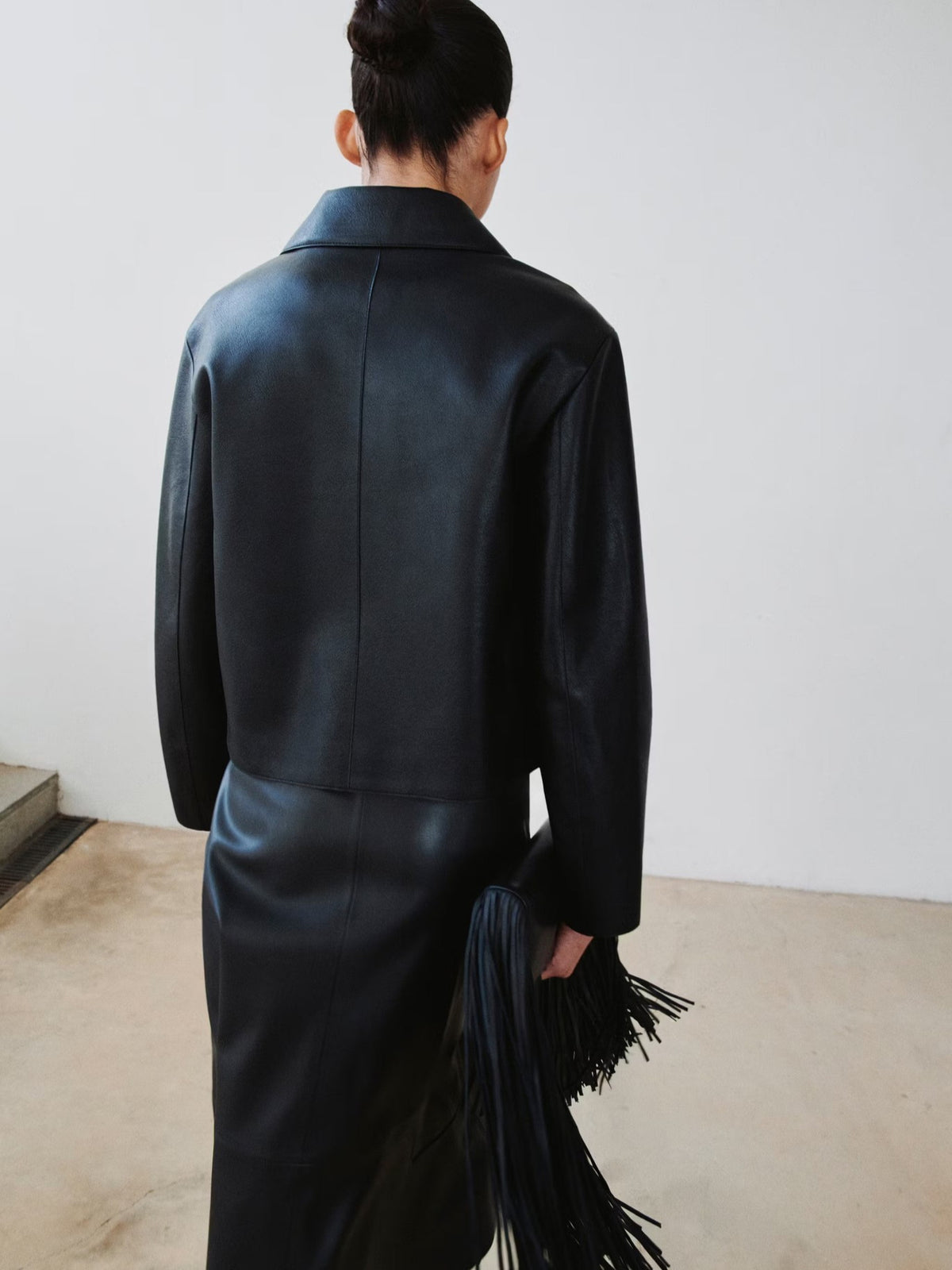 Women's black leather jacket, back view with stand collar and long sleeves
