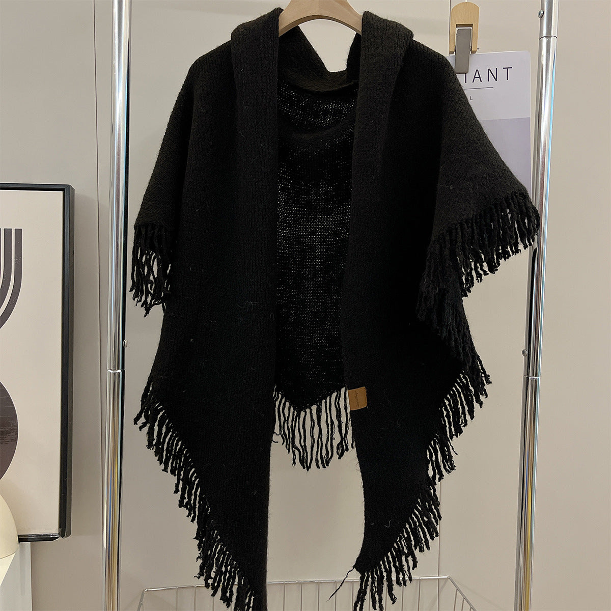 Black triangle shawl with long tassel fringe and draped silhouette on hanger