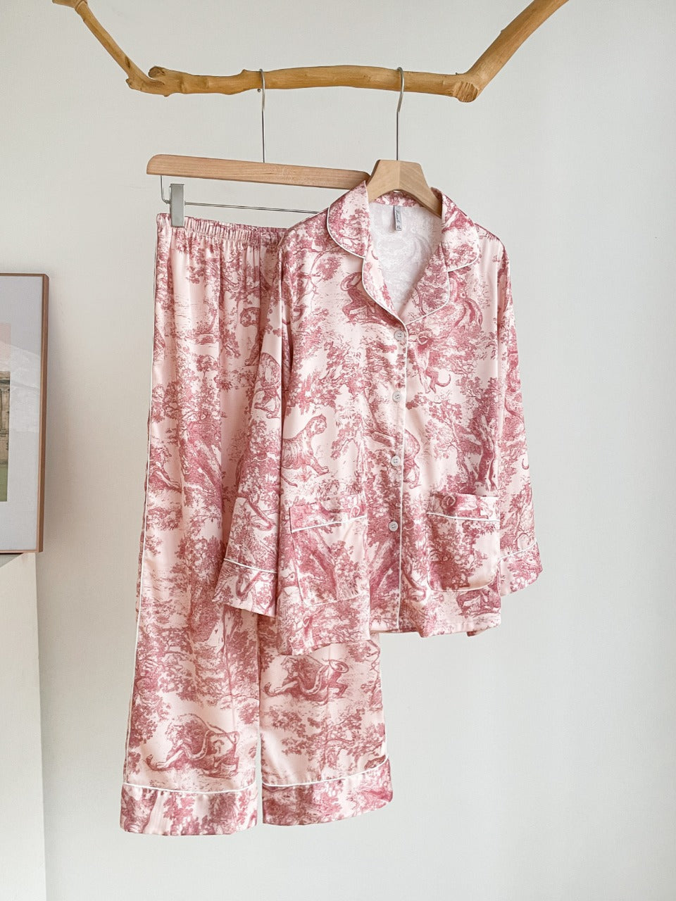 Girls’ pink jungle print pajama set hanging on a hanger, button-up shirt and pants
