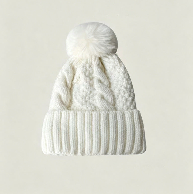 White cable-knit winter hat with ribbed cuff and fluffy pom-pom