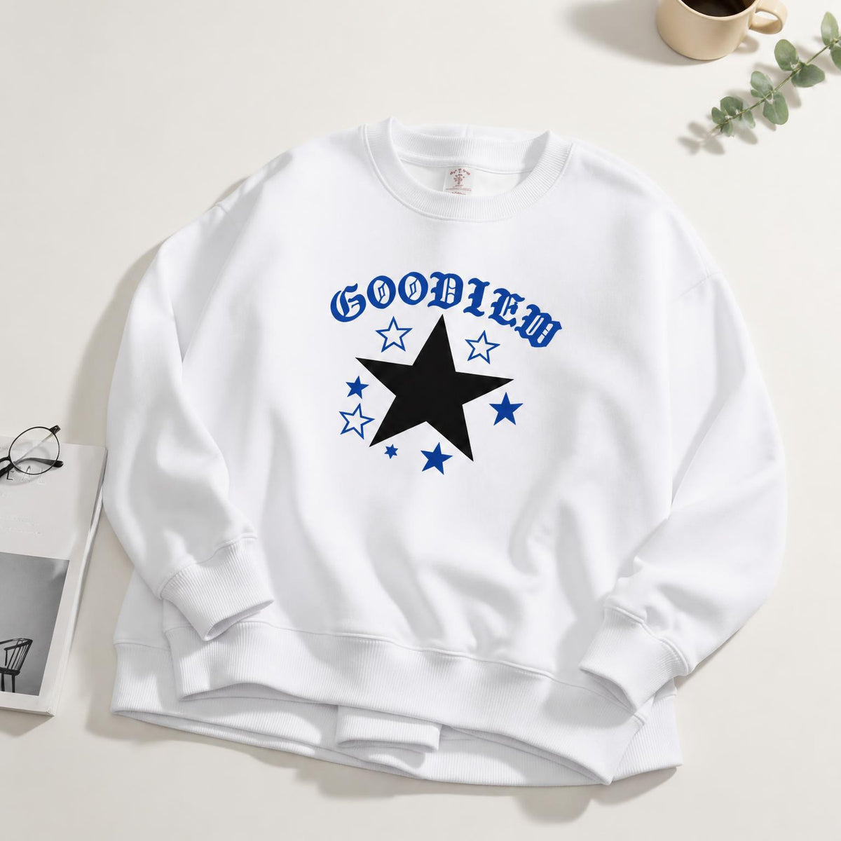 White crewneck sweatshirt with bold black and blue star graphic, relaxed long sleeves