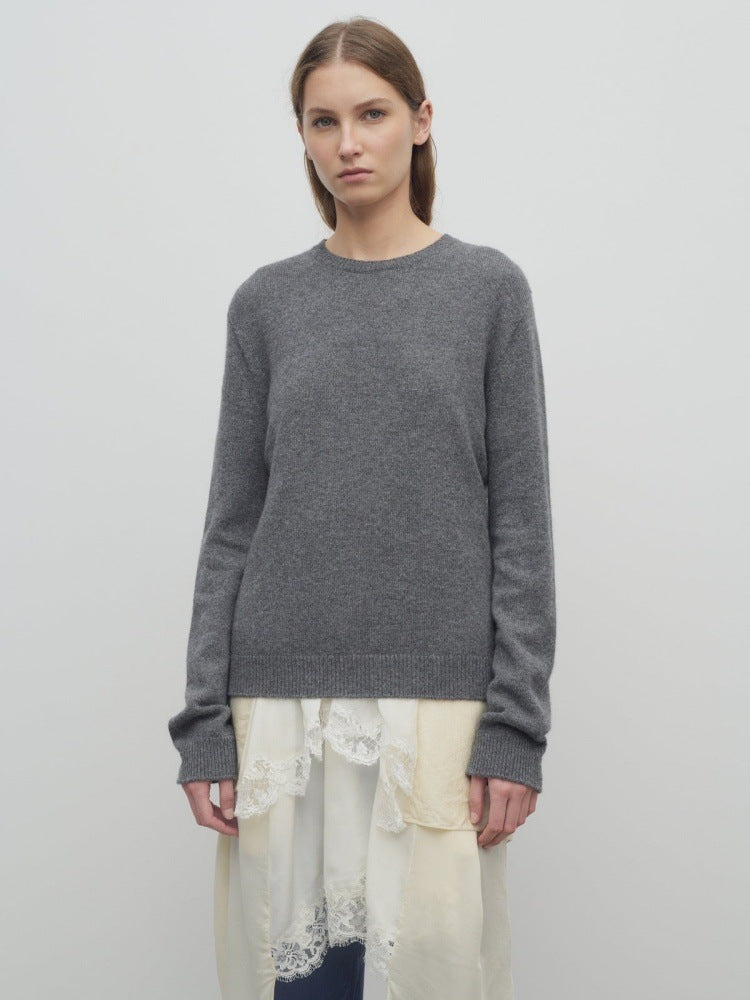 Women's gray knit pullover with long sleeves and crew neckline, paired with light skirt