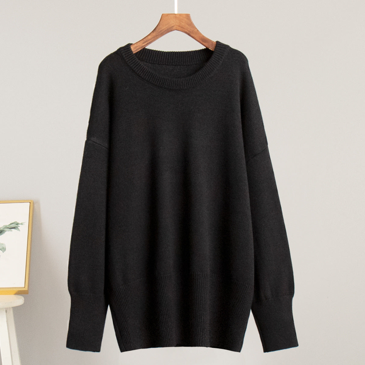 Black round-neck knit sweater on a hanger with ribbed collar and long sleeves