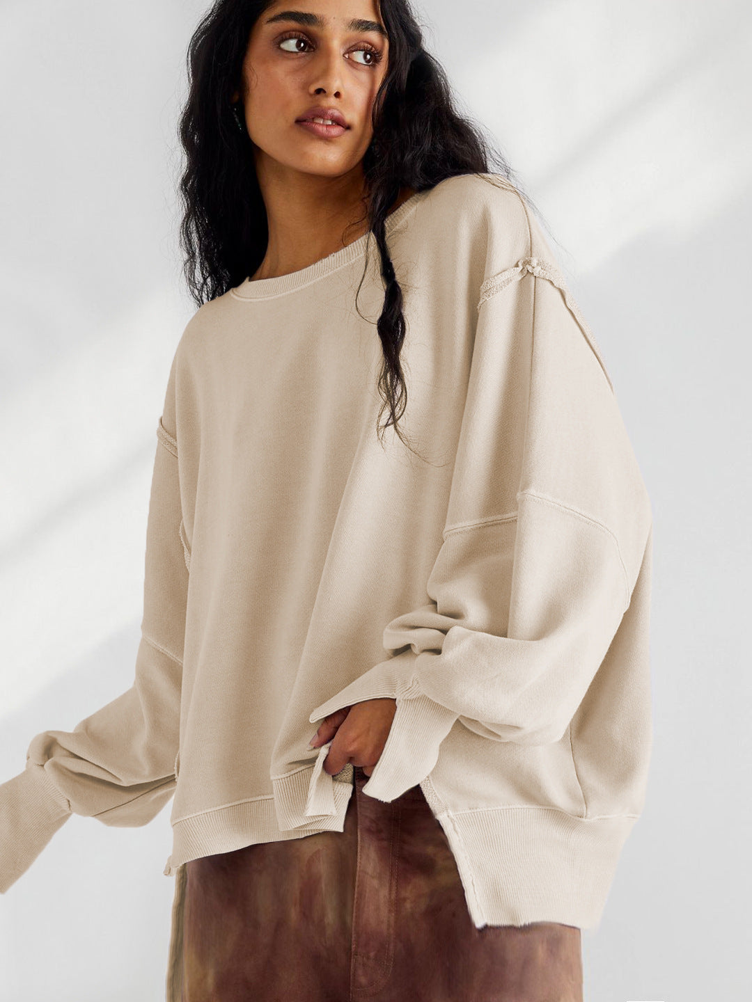 Beige oversized crewneck sweatshirt with exposed seam details and long sleeves