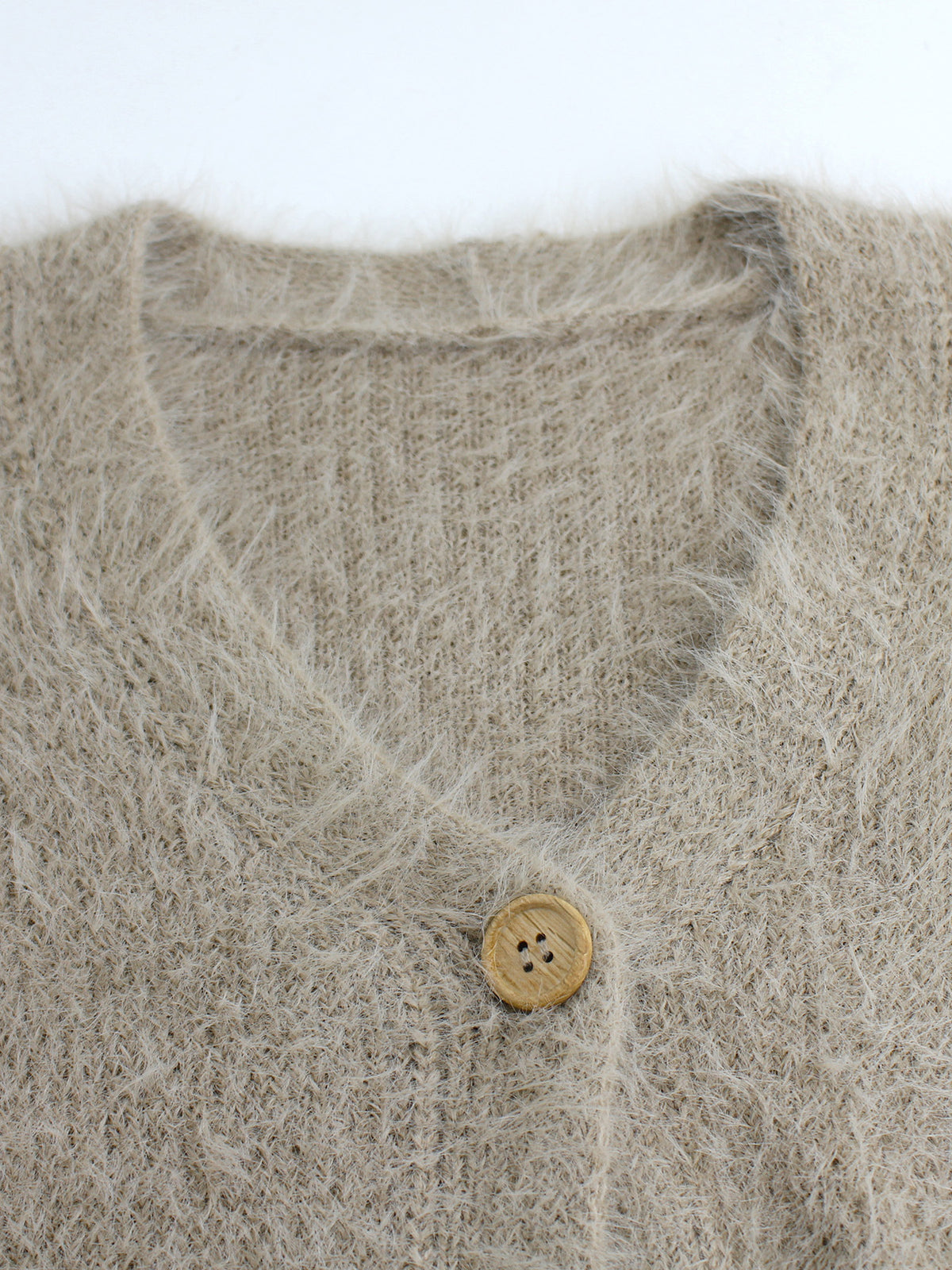 Close-up of fuzzy knit V-neck cardigan fabric and round button