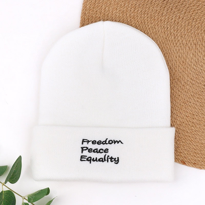 White knit beanie with “Freedom Peace Equality” text embroidery on cuff