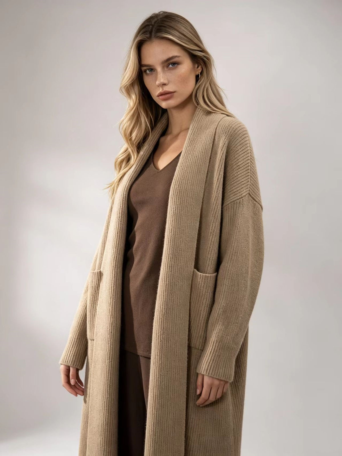 Beige knitted cardigan sweater jacket with open front, long sleeves, and patch pockets