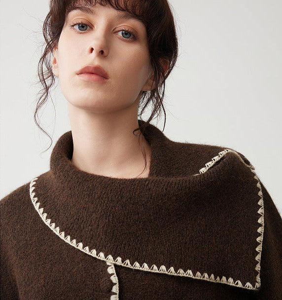 Close-up of women’s dark brown knit sweater with diagonal color block and white trim