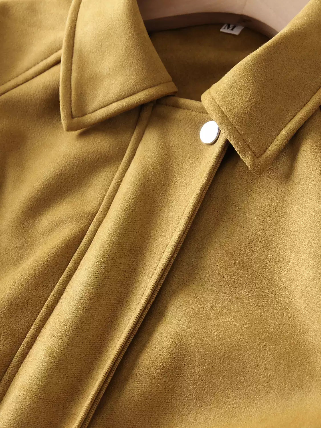Close-up of yellow faux suede bomber: stand collar, front button, and contrast seam topstitch