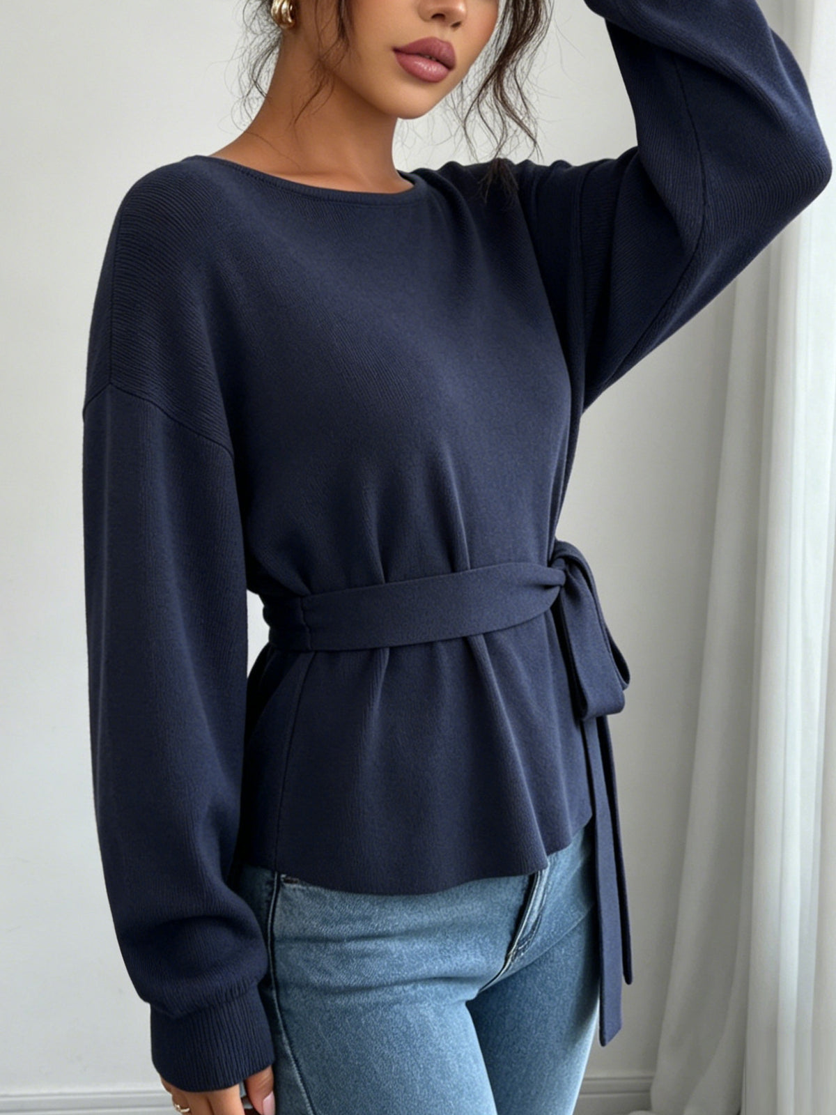 Women's dark blue knit sweater with dropped shoulders, ribbed cuffs, and a tied waist