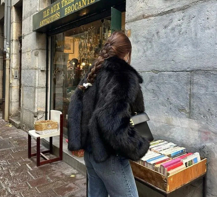 Women's dark faux fur jacket in black, pointed lapel, long sleeves.
