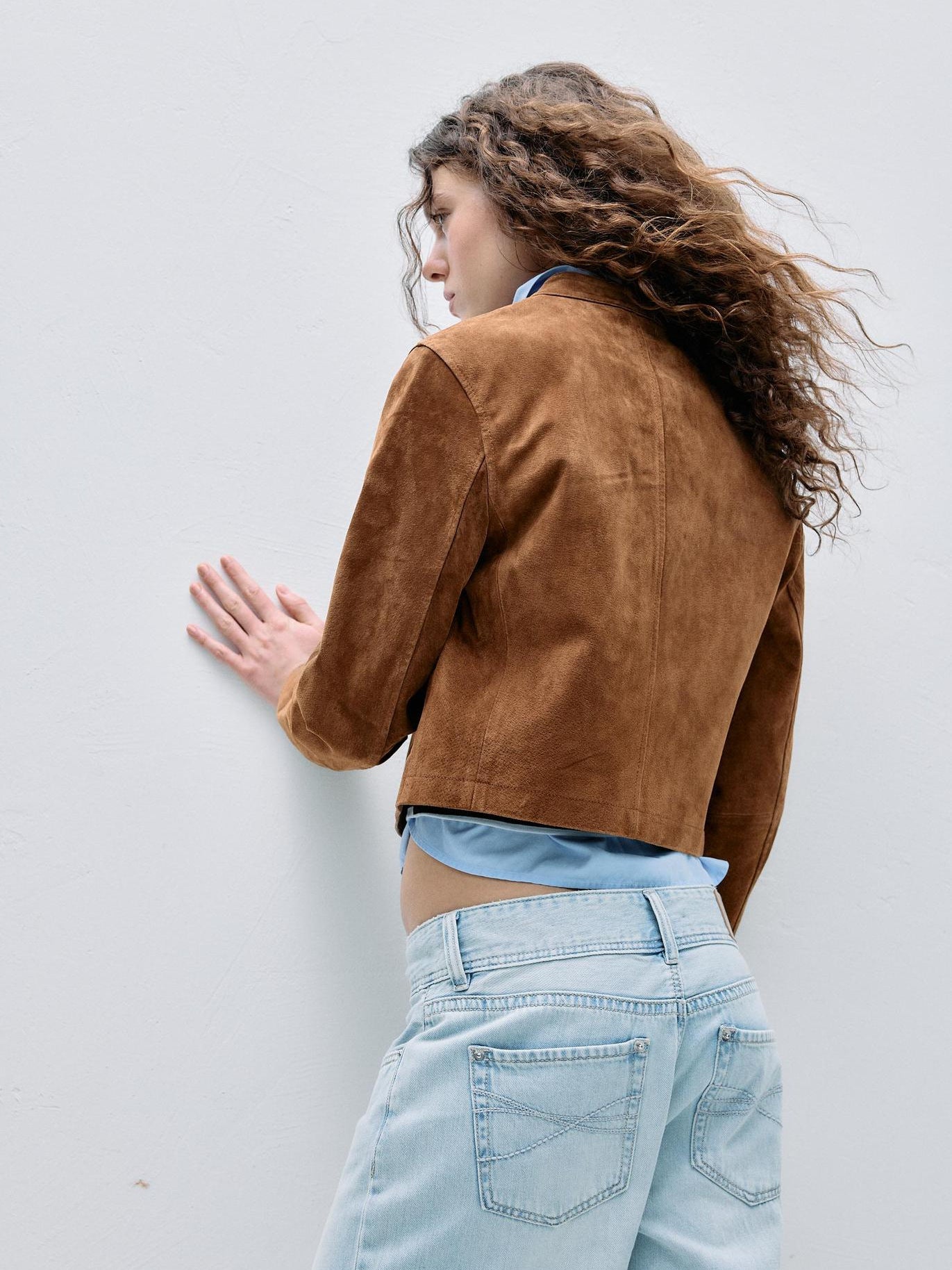 Brown faux suede moto jacket back view with curved seams and cropped hem