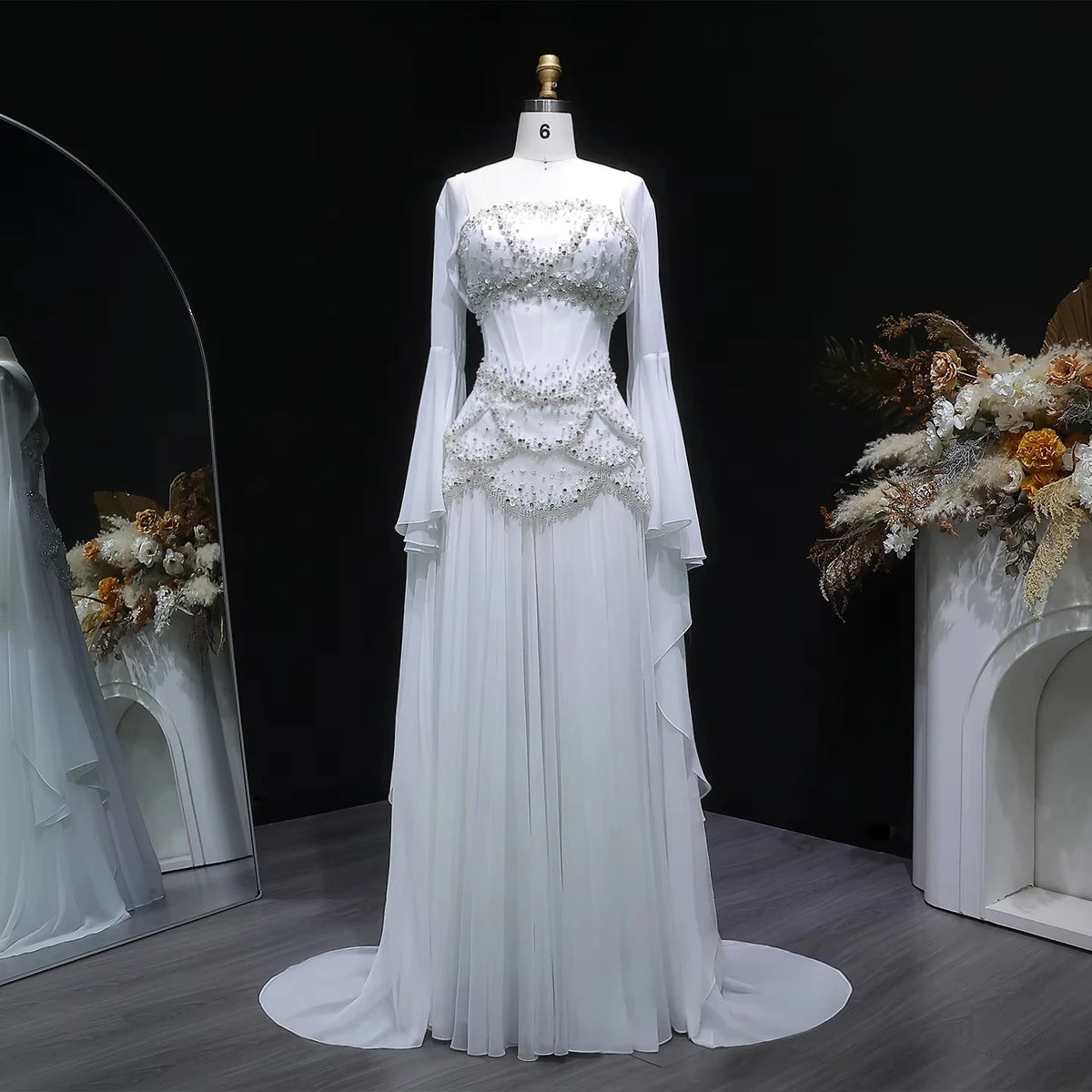 White beaded corset evening gown with a flowing skirt and long flared sleeves