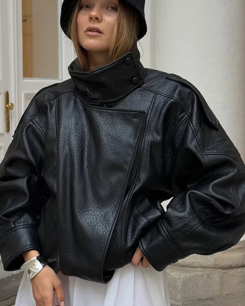 Black faux leather jacket featuring a high snap collar, wide sleeves, and diagonal front closure