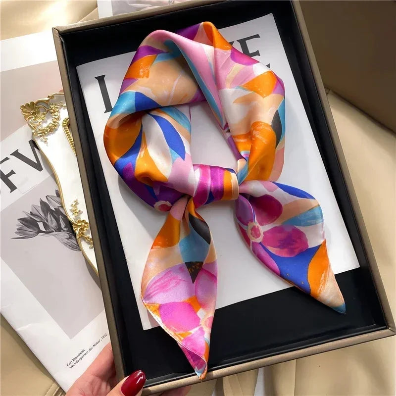 Square floral scarf with bright pink, orange, blue, and purple abstract print, tied at center