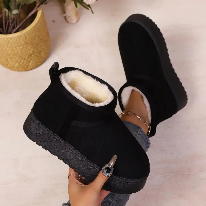 Black suede ankle boots with cream fleece lining and thick soles, held to show the side