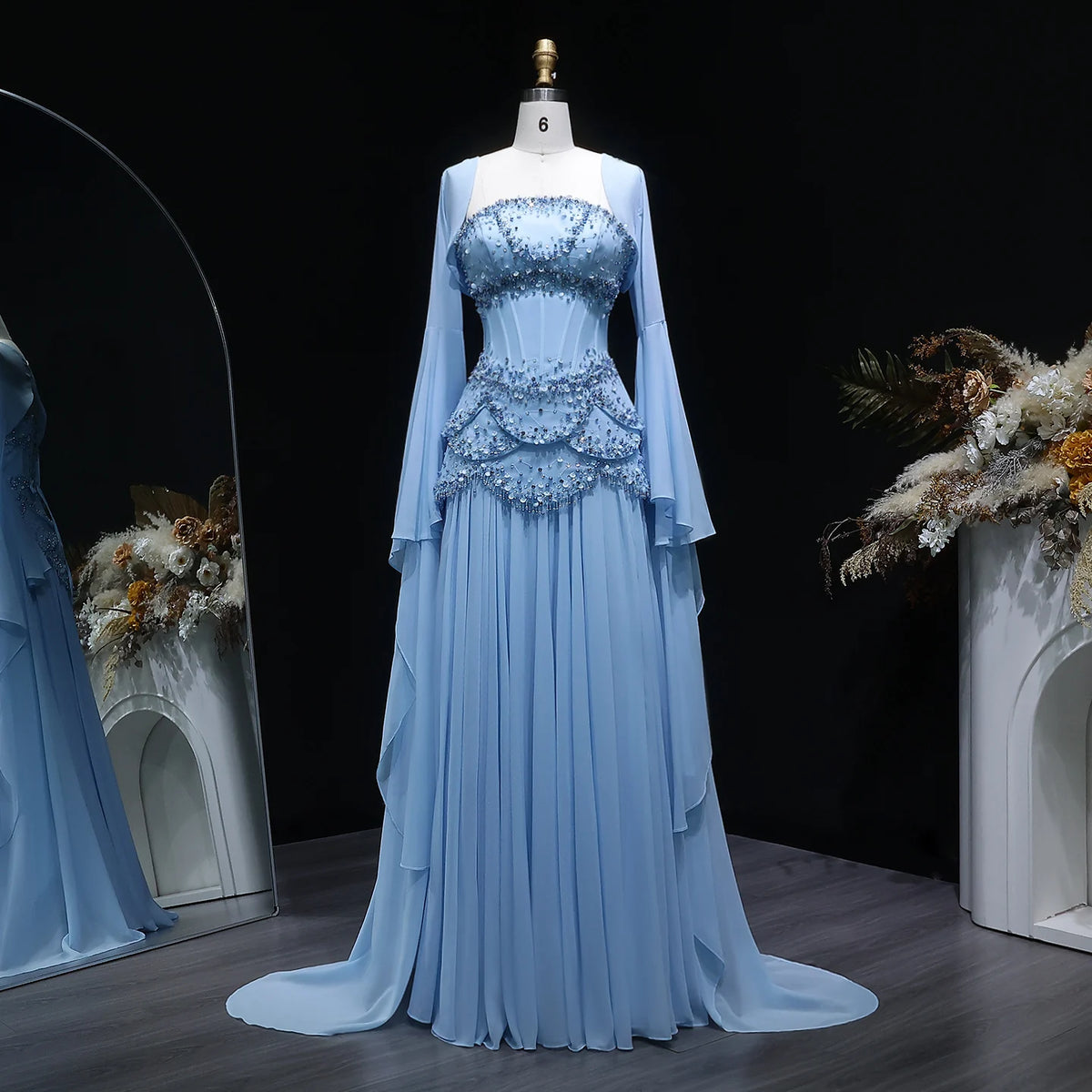Light blue beaded corset evening gown with a flowing skirt and long flared sleeves