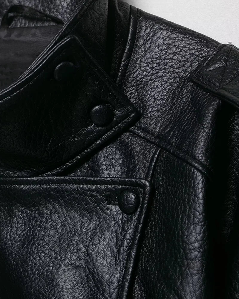 Black faux leather jacket close-up showing pebbled texture, collar snaps, and stitched panels