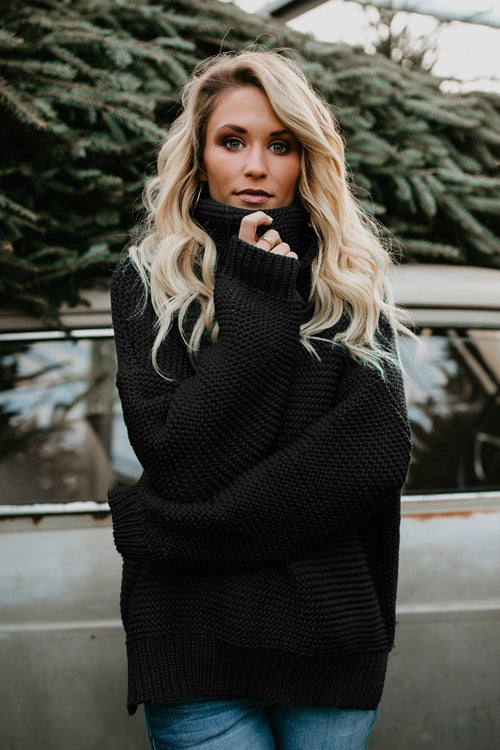 Black knit high-neck sweater with long sleeves and textured stitch pattern.
