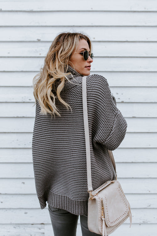 Grey-and-white striped knit high-neck sweater with long sleeves.