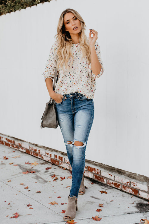 Beige dot-speckled knit sweater with crew neck, paired with blue jeans