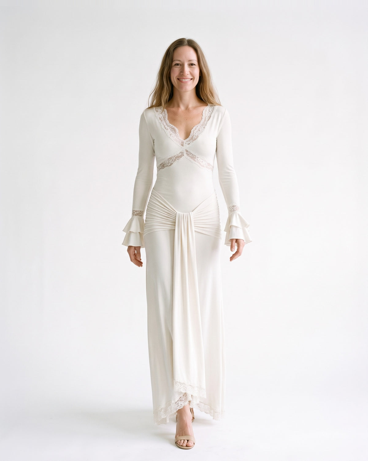 White lace long-sleeve maxi dress with V-neck, draped sash, and ruffle cuffs; full length