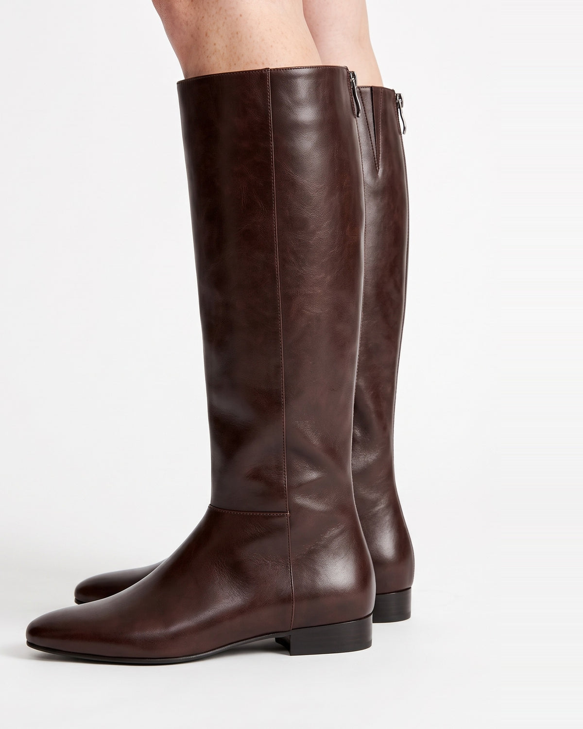 Brown leather knee-high riding boots with slim shaft and low flat heel