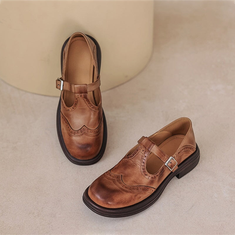 Brown leather Mary Jane flat shoes with brogue detailing and adjustable T-strap buckle.