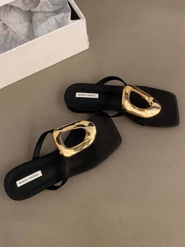 Black flat mule sandals with sculptural gold square-toe hardware and open back