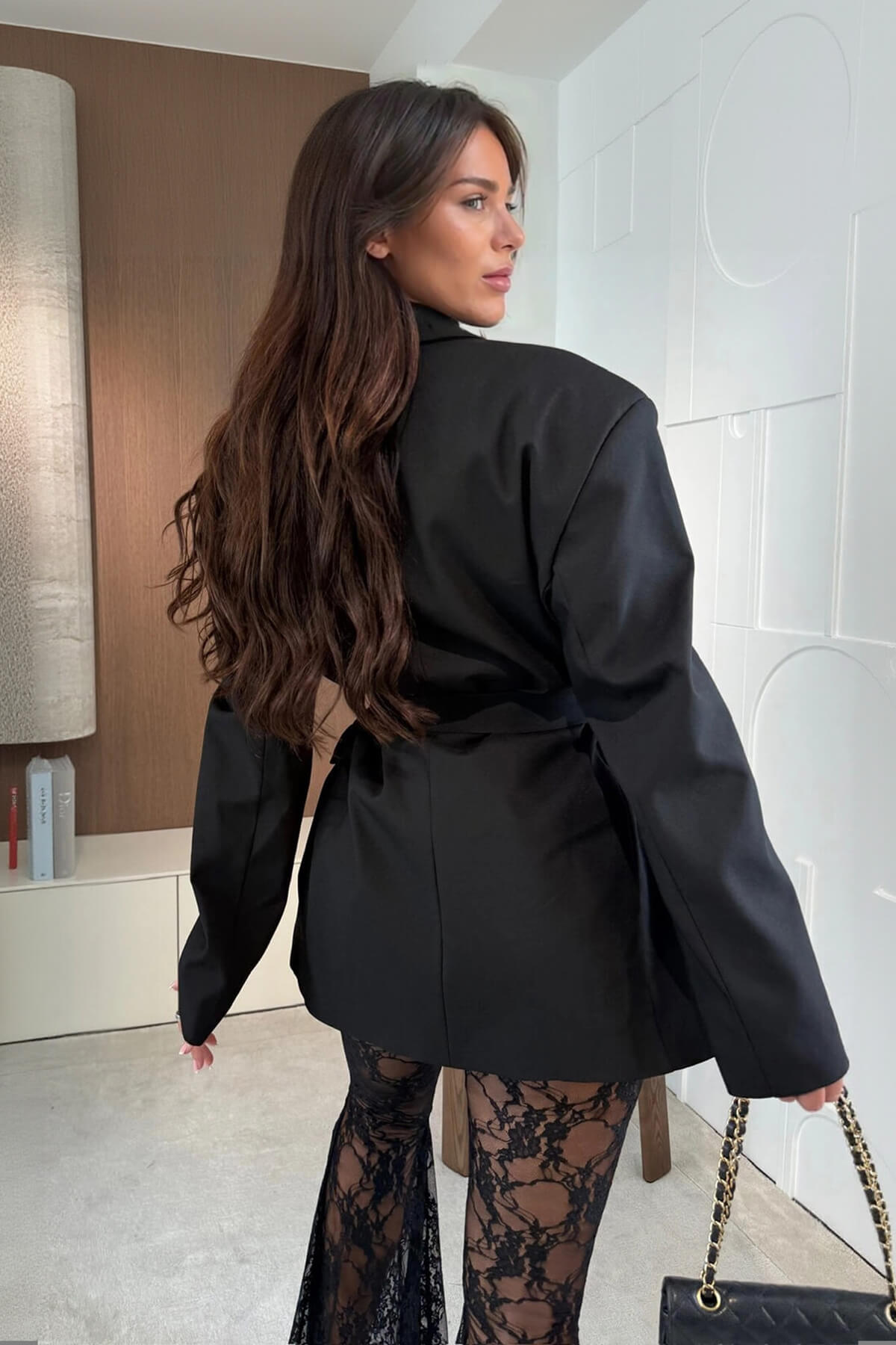 Back view of black oversized wrap blazer with belt tie and long sleeves.