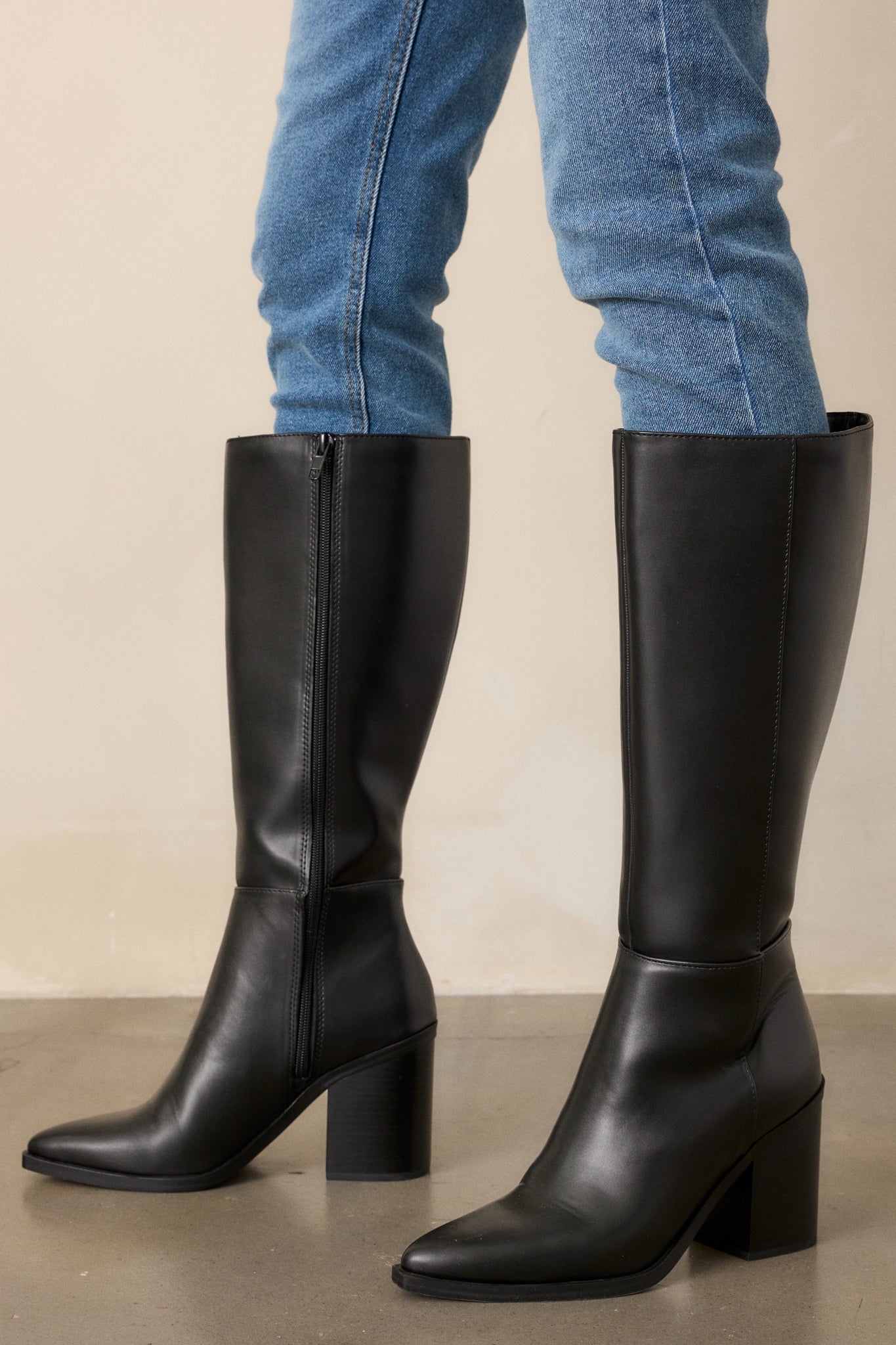 Black knee-high faux leather boots with mid block heel and straight shaft
