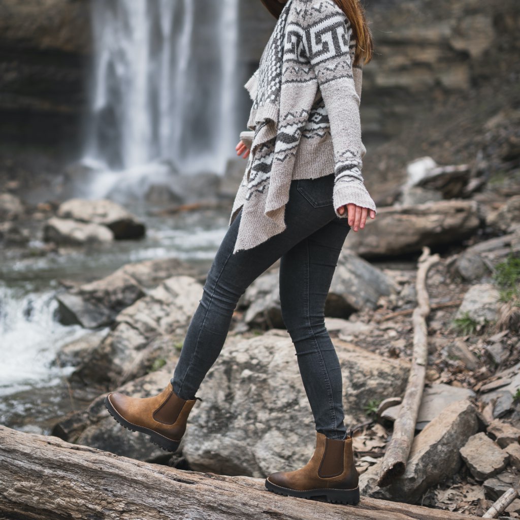 Brown suede Chelsea boots on rocky outdoor terrain, elastic gore and lug sole
