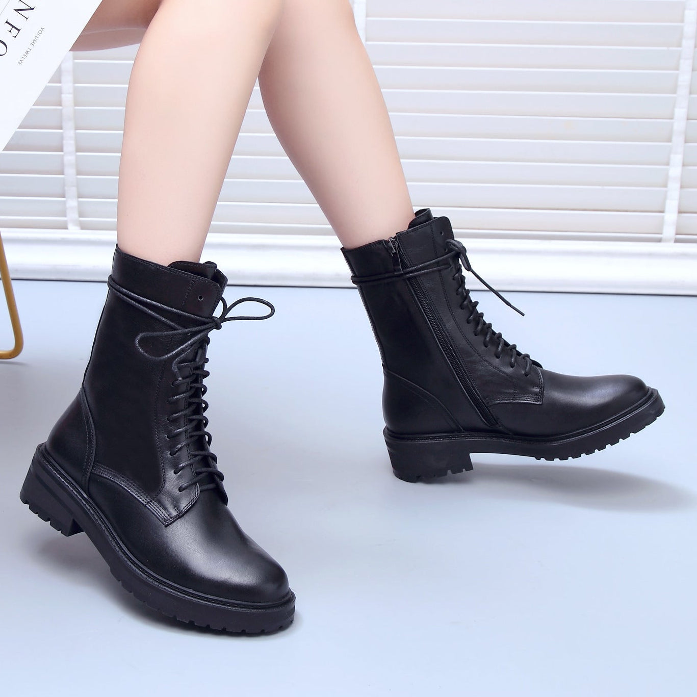 Women’s black mid-calf lace-up combat boots on model, chunky lug sole