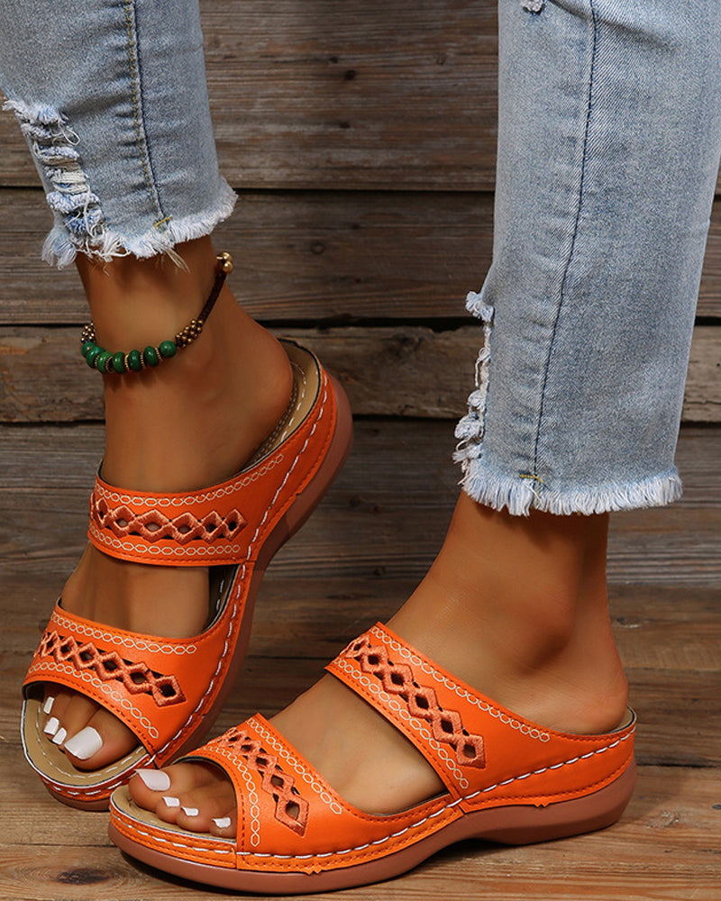 Faux leather flatform boho slide sandals in orange on feet with embroidered straps