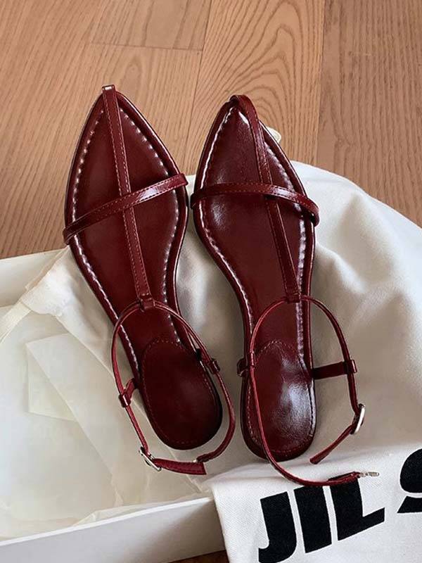Red faux leather T-strap flat sandals with pointed toe and adjustable ankle strap