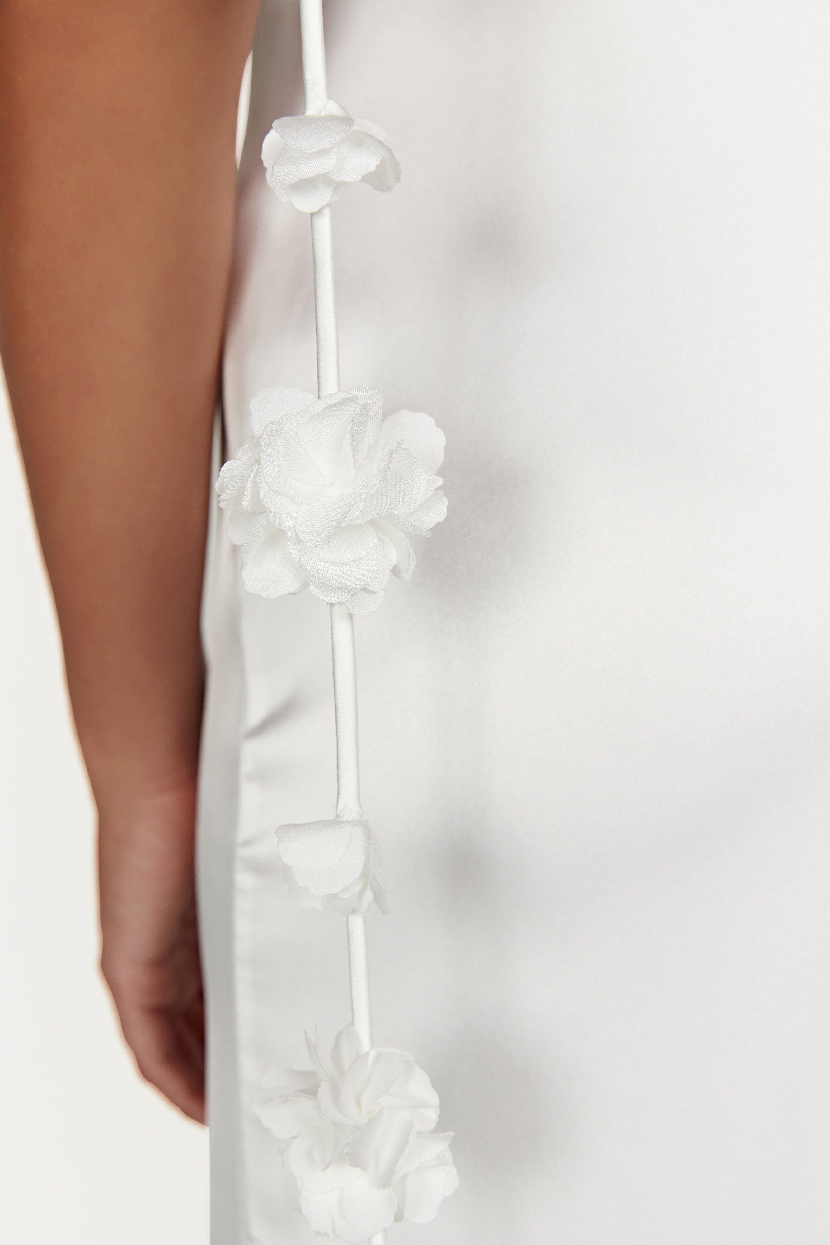 Close-up of 3D floral strap embellishments on a white satin dress